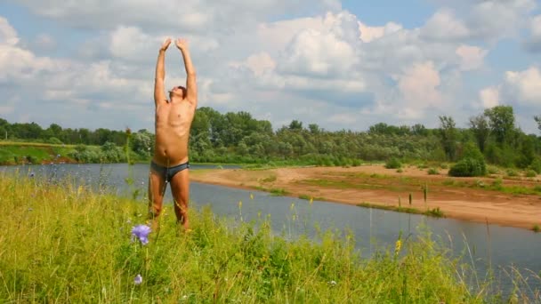 Man with hands up on the river, summer — Stockvideo